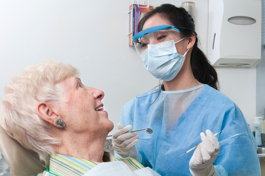 Dentist performing an oral health exam on an older adult.
