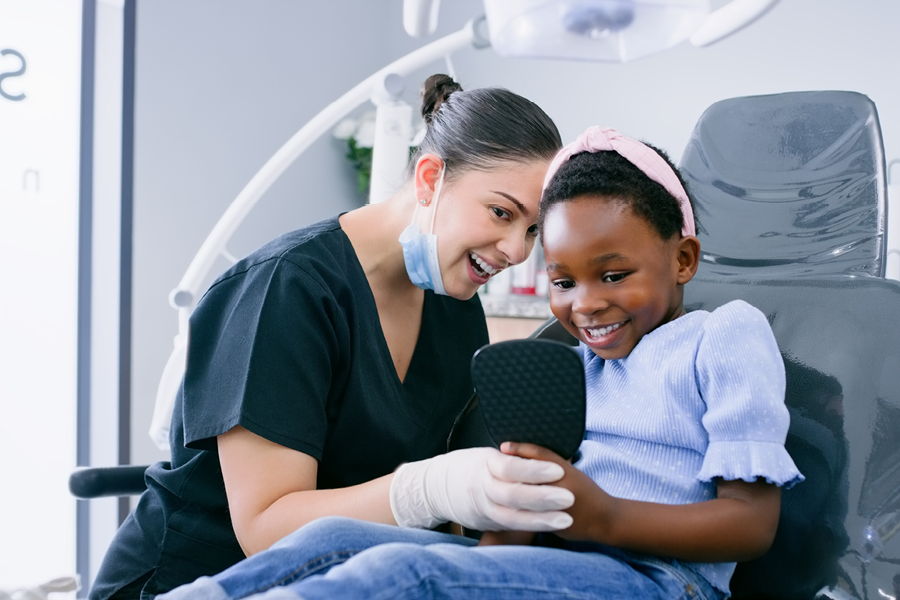 Dental assistant and patient smiling in the dental chair.