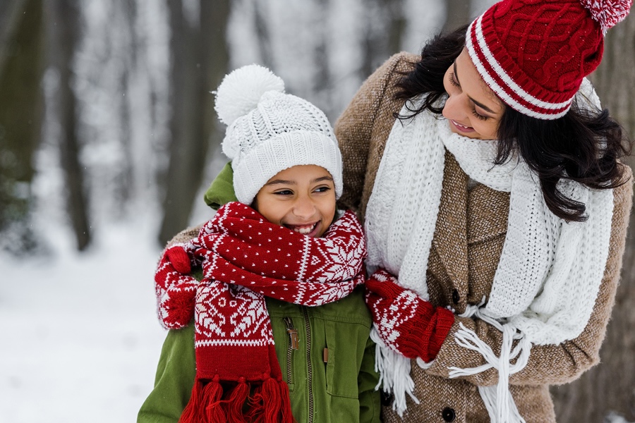 Mother and daughter smiling outside in the cold together.