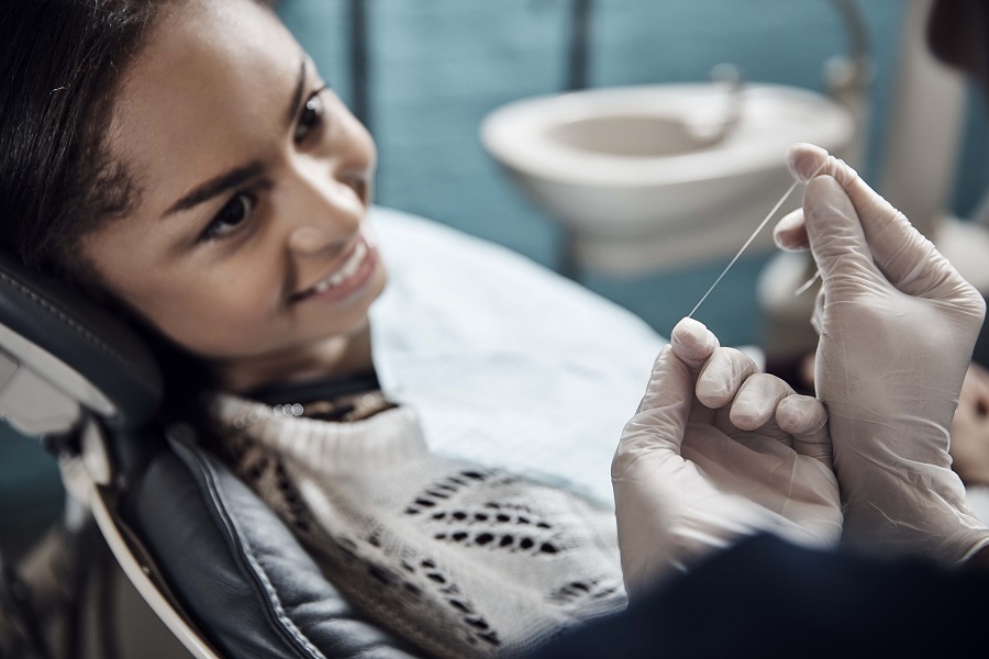 Women sitting in dentist chair about to get her teeth flossed by the dentist