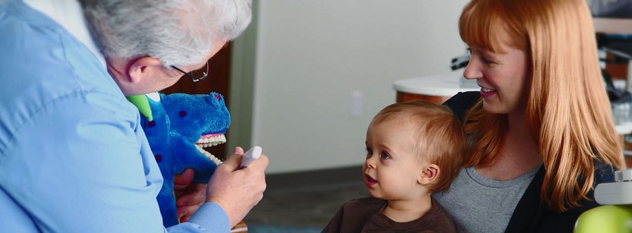 Dentist showing a baby how to brush their teeth