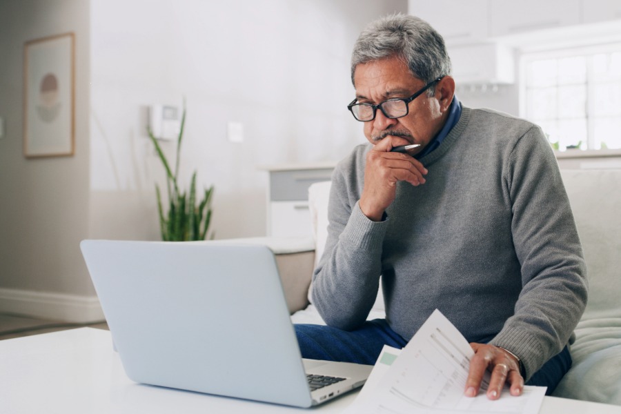 man looking at his computer and papers on his desk