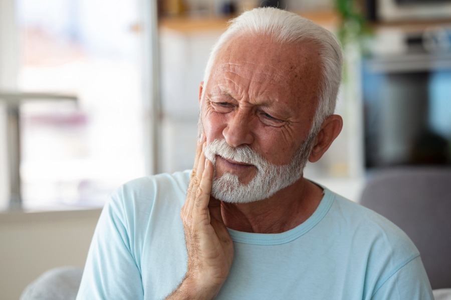 senior man touching his jaw with pain