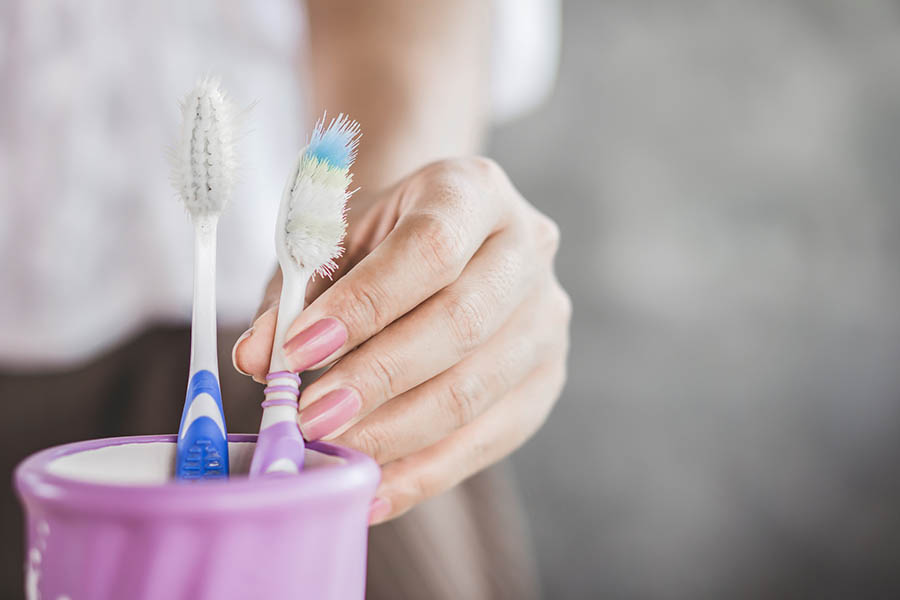 one new and one old toothbrush in a cup